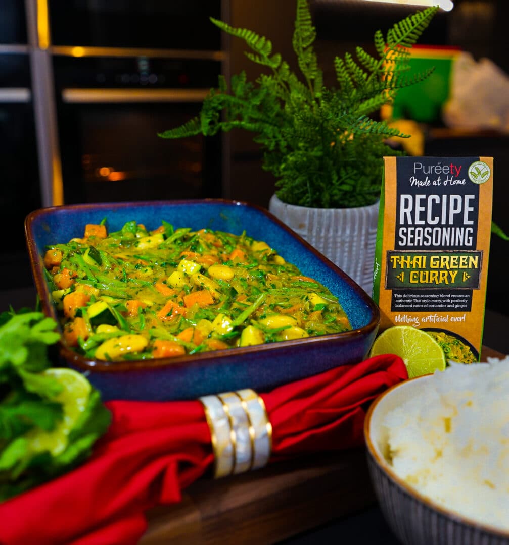 Plant based butterbean and sweet potato thai curry in serving dish next to product 