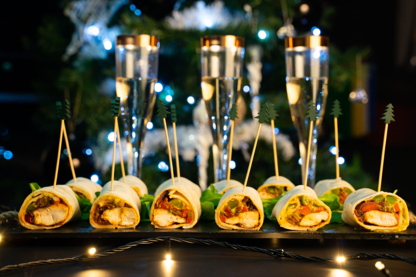 Tray of mini fajitas with a backdrop of wine glasses and Christmas tree